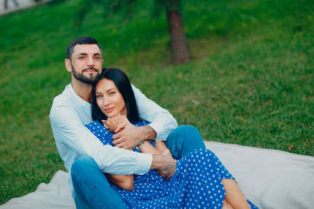 Young adult woman and man hugging couple picnic at green grass meadow in parkの写真素材