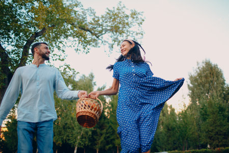 Happy Couple with Fruits in Picnic Basket Running in the Parkの写真素材