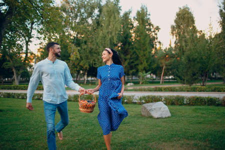 Happy Couple with Fruits in Picnic Basket Running in the Parkの写真素材