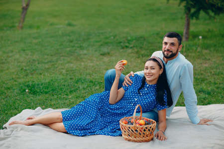 Young adult woman and man couple picnic sitting at green grass meadow in parkの写真素材