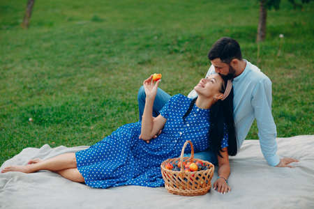 Young adult woman and man couple picnic sitting at green grass meadow in parkの写真素材