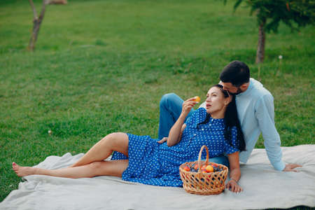 Young adult woman and man couple picnic sitting at green grass meadow in parkの写真素材