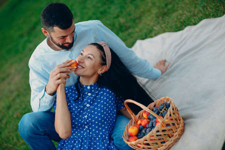 Young adult woman and man couple picnic at green grass meadow in parkの写真素材