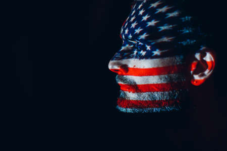 Adult man with USA flag on his face in the dark. Independence Day conceptの写真素材