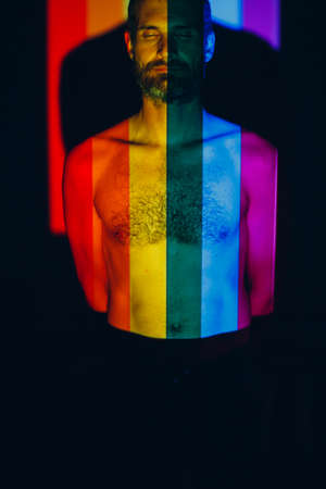 Rainbow Flag on face of adult man in darkの写真素材