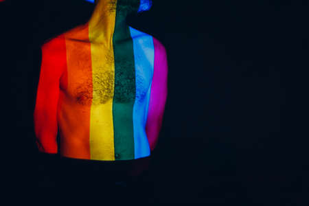 Rainbow Flag on body of adult man in darkの写真素材