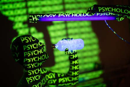 Young adult man drinking bottled water in ultraviolet light with letters and words