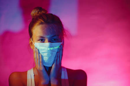 Woman wearing medical face mask in dark.