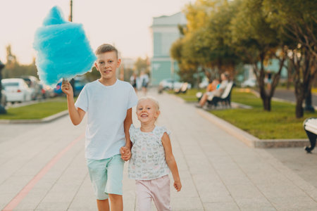 Happy children boy and girl eating blue cotton candy outdoors.の写真素材