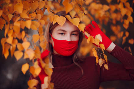 Active young woman in red gloves and face mask at autumn park.の写真素材