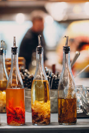 Olive oil in bottle with garlic, red pepper and rosemary on table in pizzeria.の写真素材