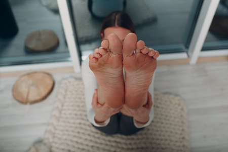 Adult woman doing yoga at home living room with online tutorials on laptopの写真素材