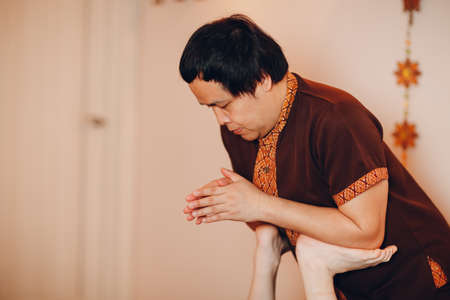 Thai man making classical thai massage procedure to young woman at beauty spa salonの写真素材