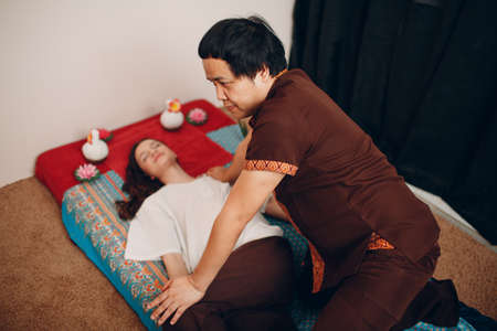 Thai man making classical thai massage procedure to young woman at beauty spa salonの写真素材