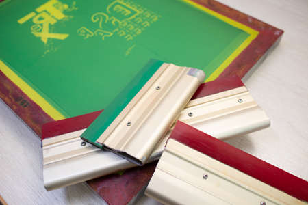Serigraphy silk screen print process at clothes factory. Frame stencil and squeegee.の写真素材