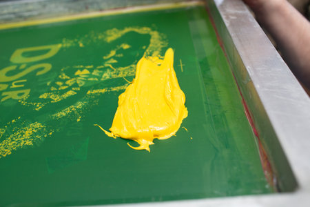 Serigraphy silk screen print process at clothes factory. Frame, squeegee and plastisol color paints.の写真素材