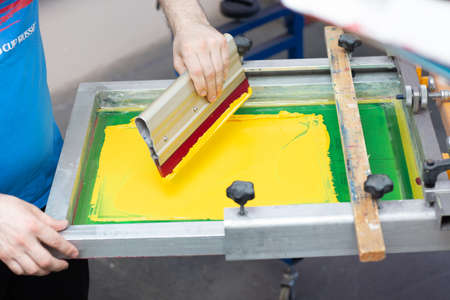 Serigraphy silk screen print process at clothes factory. Frame, squeegee and plastisol color paints.の写真素材