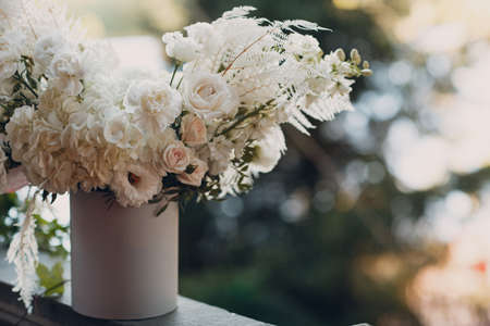 Bouquet of white roses and other white flowers in a cardboard round box on a green background.の写真素材