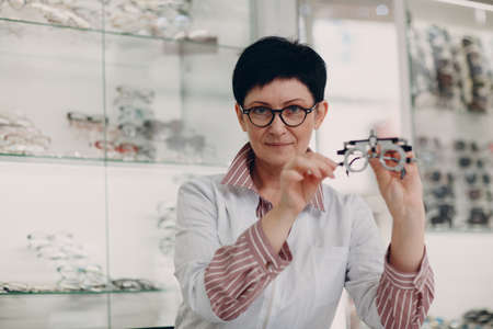 Happy Optician Choosing Eyeglasses, female optometrist with glasses.の写真素材