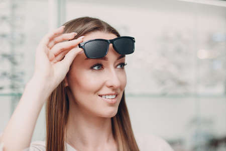 Young Woman with Black punched eyeglasses for vision training. perforated glasses trainer.の写真素材