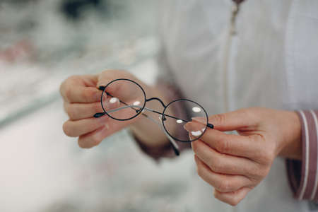 Women hand with trendy glasses lens. Eyeglasses transparent diopter.の写真素材