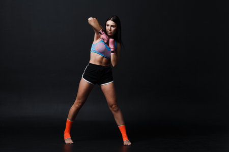 Sportsman muay thai woman boxer posing in training studioの写真素材