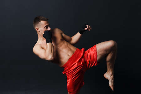 Sportsman muay thai man boxer stance ad knee kick at black background.の写真素材