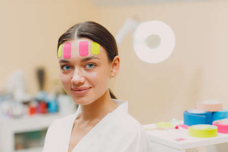 Beautiful woman applying tape lifting treatment procedure on faceの写真素材