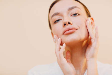 Young caucasian woman doing facebuilding yoga facial gymnastics self lymph facelift massage.の写真素材