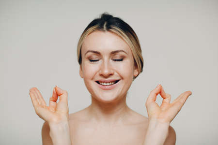 Inner peace and yoga, zen, meditation concept. Smiling young adult woman practicing yoga and show okay sign mudra with both handsの写真素材