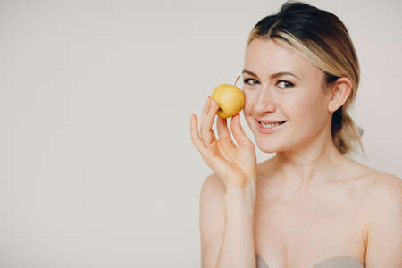 Young lovely woman with apple near face, skin natural care cosmetics conceptの写真素材