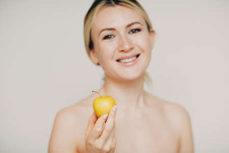 Young lovely woman with apple near face, skin natural care cosmetics conceptの写真素材