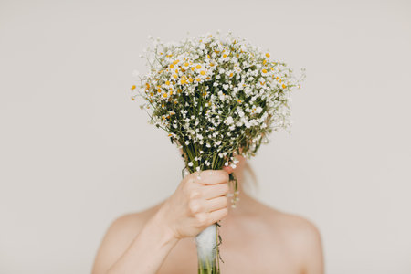 Young and beautiful blonde woman with camomile bouquet. Natural eco cosmetics conceptの写真素材