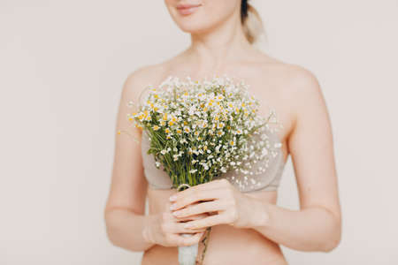 Young and beautiful blonde woman with chamomile bouquet. Natural eco cosmetics conceptの写真素材