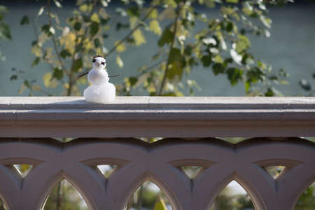 Little snowman on a fence with tree.の写真素材