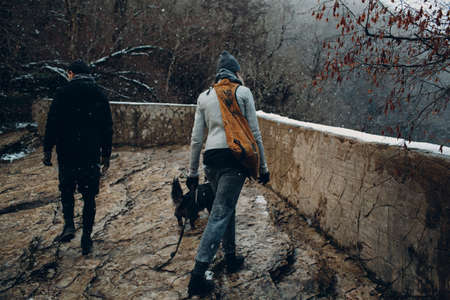Young couple walking with corgi dog in the winter park.の写真素材