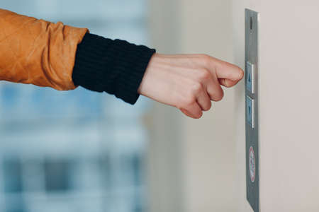 Close up of forefinger pressing the button elevator
