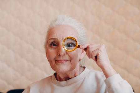 The elderly woman with magnifier loupe in hand.の写真素材