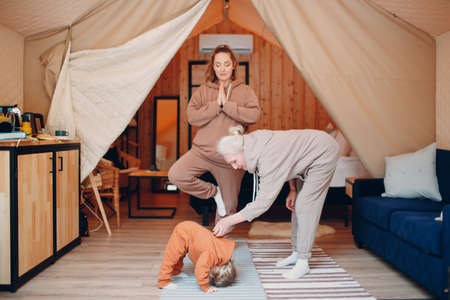 Family doing exercises sports idoors. Young and senior elderly woman relaxing at glamping camping tent. Mother and daughter modern vacation lifestyle conceptの写真素材
