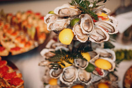 oysters with lemon on a platter in a restaurant on a white table catering.の写真素材