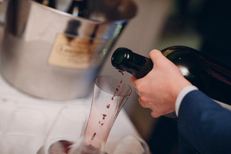 the waiter pours elite red wine into the decanter on the table in the restaurant.の写真素材