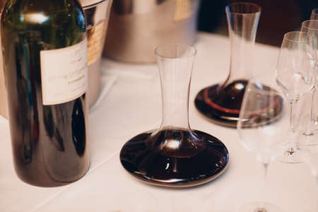 the waiter pours elite red wine into the decanter on the table in the restaurant.の写真素材