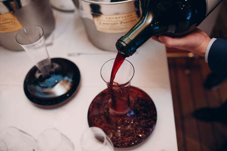 the waiter pours elite red wine into the decanter on the table in the restaurant.の写真素材