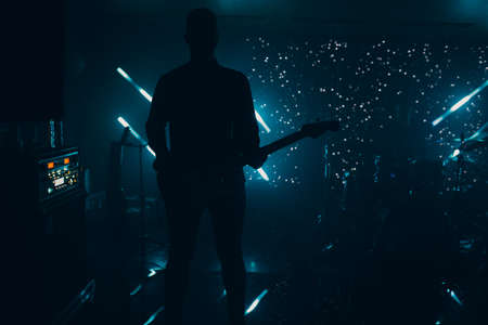 silhouette of a guitarist on a dramatic illuminated dark stage with a guitar night life concert rock.の写真素材