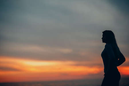 Young woman silhouette on the seashore pebble beachの写真素材