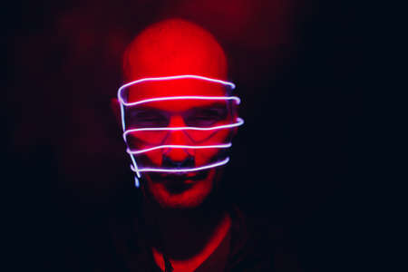 Portrait of man with neon glow lines on his face. Concept cyberpunk and virtual realityの写真素材