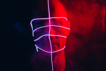 Portrait of man with neon glow lines on his face. Concept cyberpunk and virtual realityの写真素材