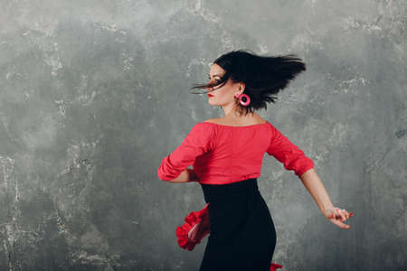 Young adult spanish woman dancing flamenco on gray vintage studio backgroundの写真素材