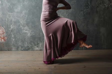 Young adult spanish woman dancing flamenco on grey vintage studio backgroundの写真素材