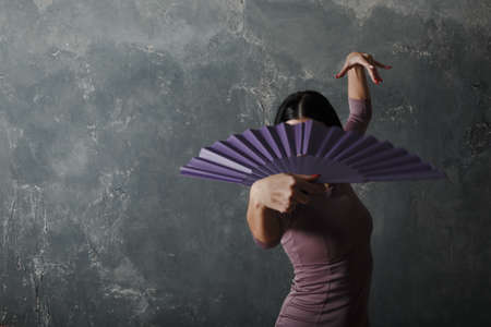 Young adult spanish woman dancing flamenco on gray vintage studio backgroundの写真素材